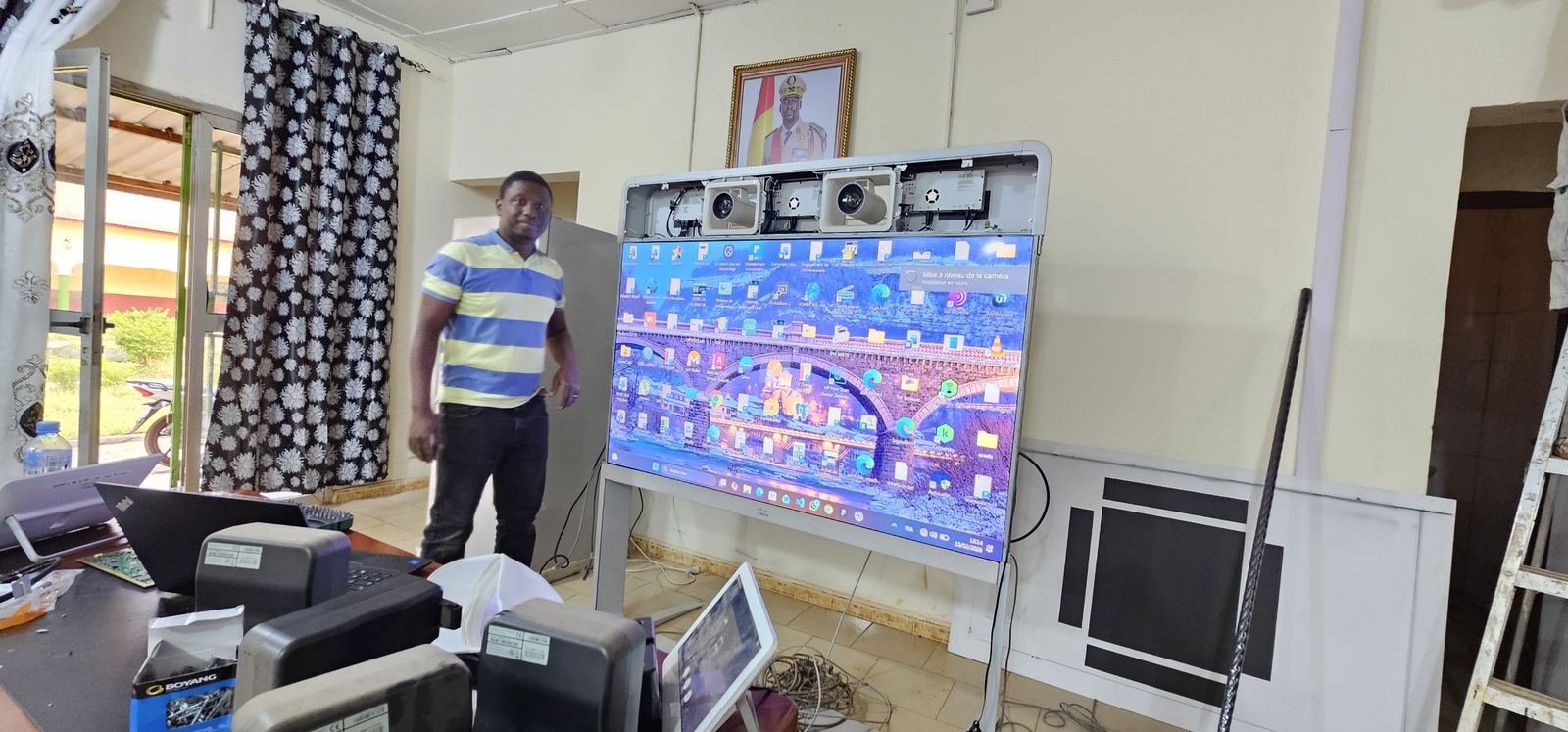 Technicien GENESIS-GUINÉE lors de l'installation d'un écran interactif dans un bâtiment institutionnel à Mamou