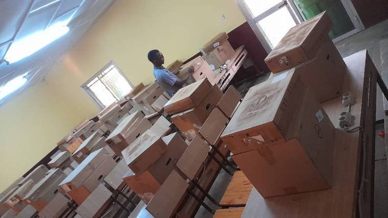 Salle remplie de cartons d'équipements, technicien en train de trier la livraison
