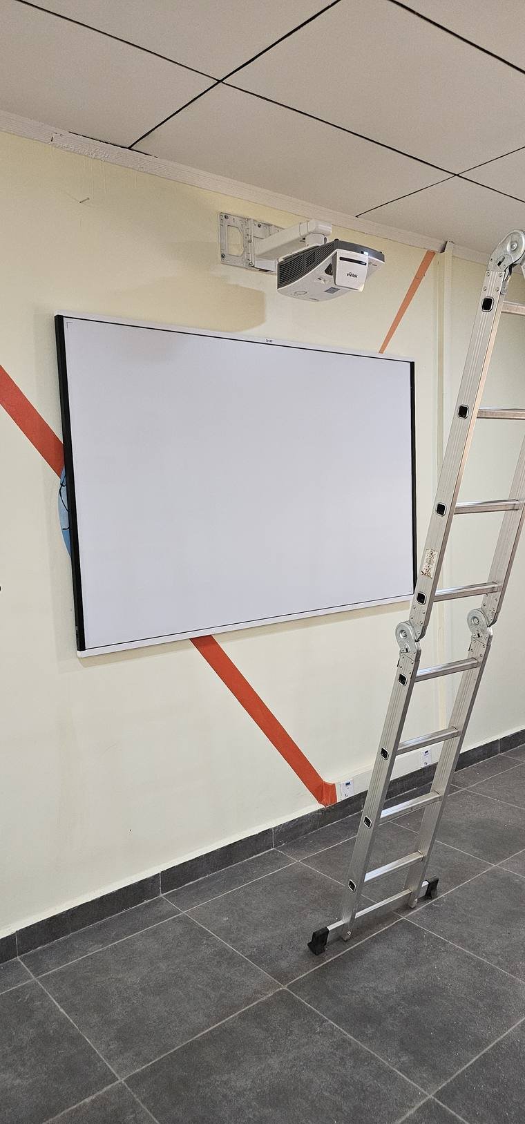 Tableau blanc interactif et vidéoprojecteur fixés au mur, installation en cours